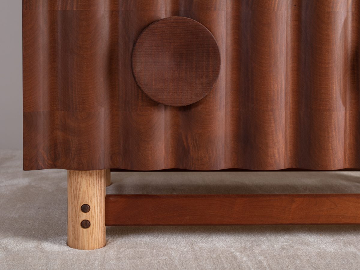 Bowater Chest of Drawers, a tiered four drawer unit. The signature ripple facade is digitally profiled from brown oak, hand-turned leg and handle details with a removable base, The carcass is made from solid timber with dovetail joinery