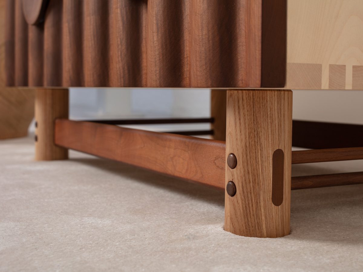 Bowater Chest of Drawers, a tiered four drawer unit. The signature ripple facade is digitally profiled from brown oak, hand-turned leg and handle details with a removable base, The carcass is made from solid timber with dovetail joinery