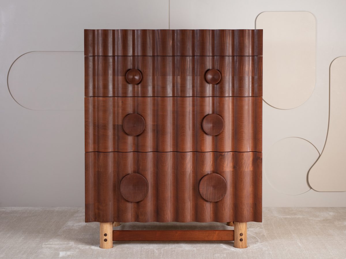 Bowater Chest of Drawers, a tiered four drawer unit. The signature ripple facade is digitally profiled from brown oak, hand-turned leg and handle details with a removable base, The carcass is made from solid timber with dovetail joinery